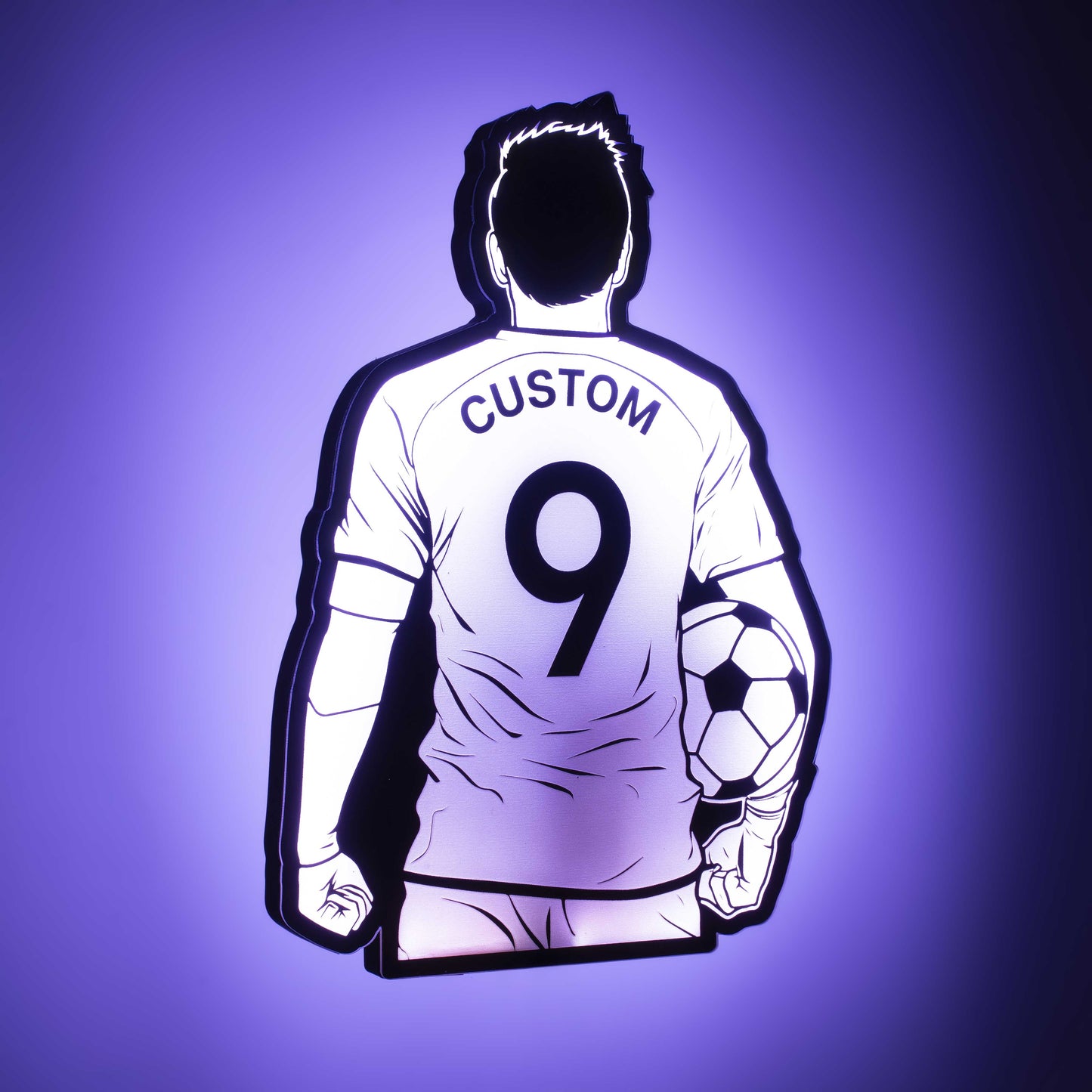 a 3d wall mounted acrylic light, back-lit by  multi-color led lights, featuring a cartoon style illustration of soccer player holding a soccer ball under his arm, view from behind showing the back of the soccer players jersey. The text and number on the back of the jersey can be personalised.